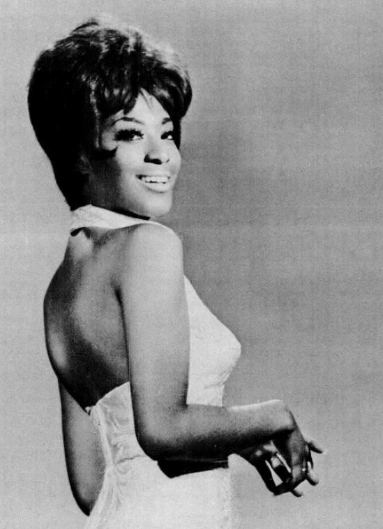 Black-and-white portrait of Marlena Shaw smiling over her shoulder in a sleeveless white dress.