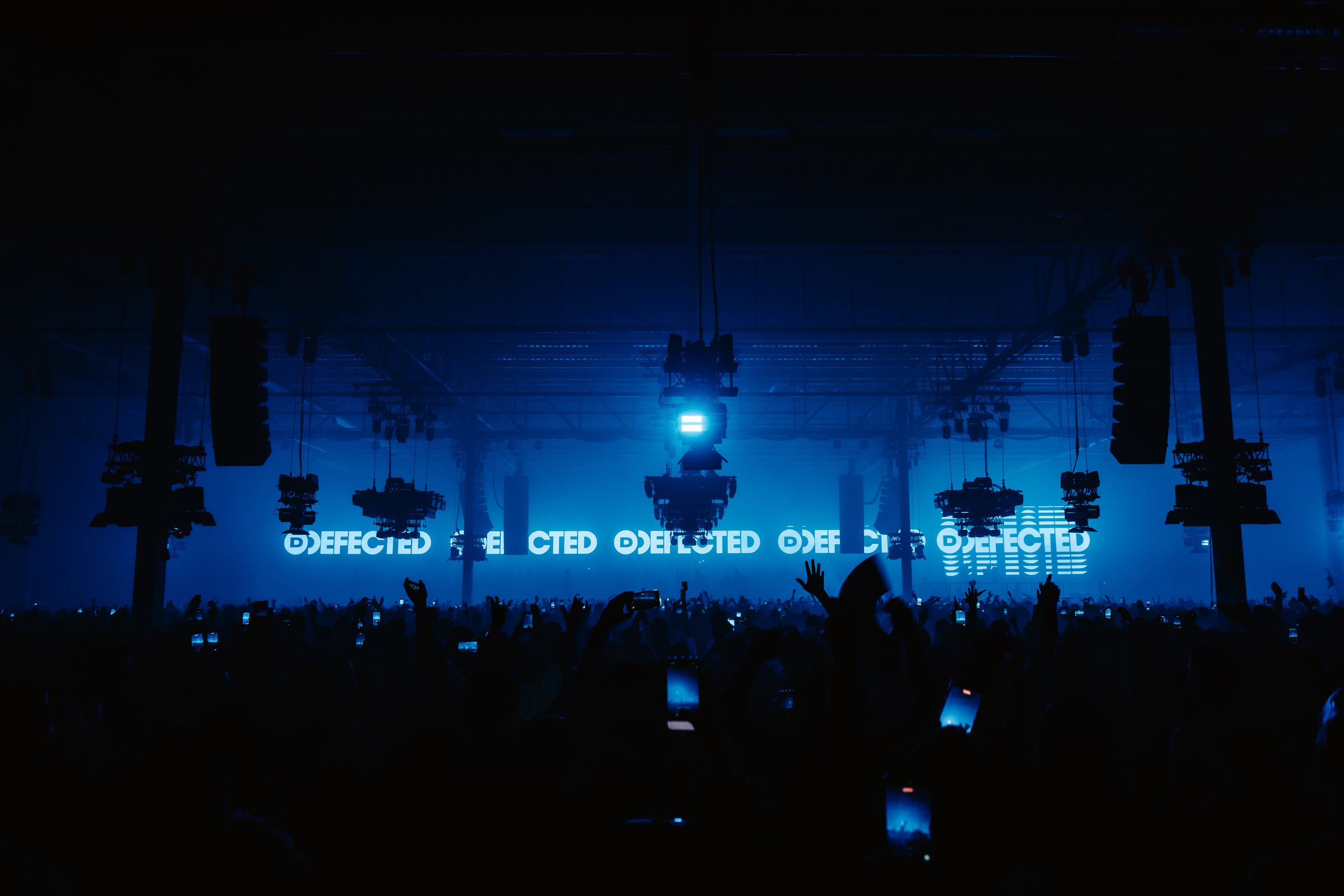 Defected main room at Drumsheds lit blue with a packed crowd and Defected branding
