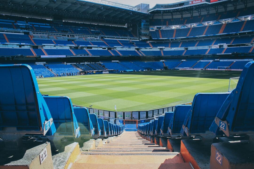 An empty football stadium and pitch viewed from the stands in daylight.